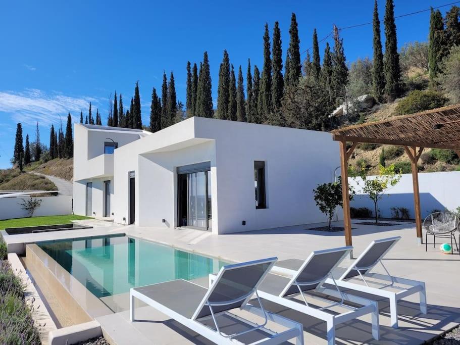 uma villa branca com uma piscina e cadeiras em Nafplio Villa, pool & sea view em Tolo