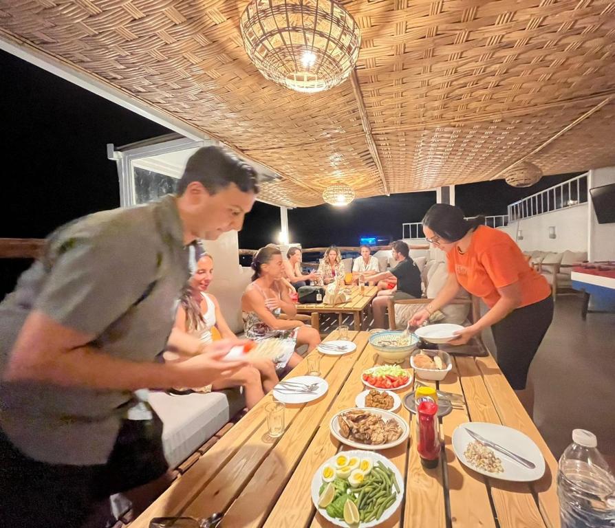 un grupo de personas de pie alrededor de una mesa con comida en BigBlue Hostel - Taghazout, en Taghazout