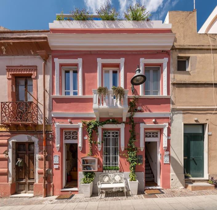 un bâtiment rose avec un banc devant lui dans l'établissement CHARMING HOUSE con doccia sensoriale e cortile interno - CENTRO STORICO, à Cagliari