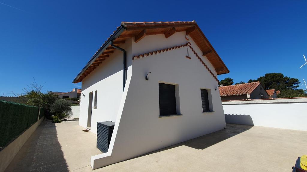 a white building with a brown roof at Maison Bord de mer refaite à neuf in Canet-en-Roussillon