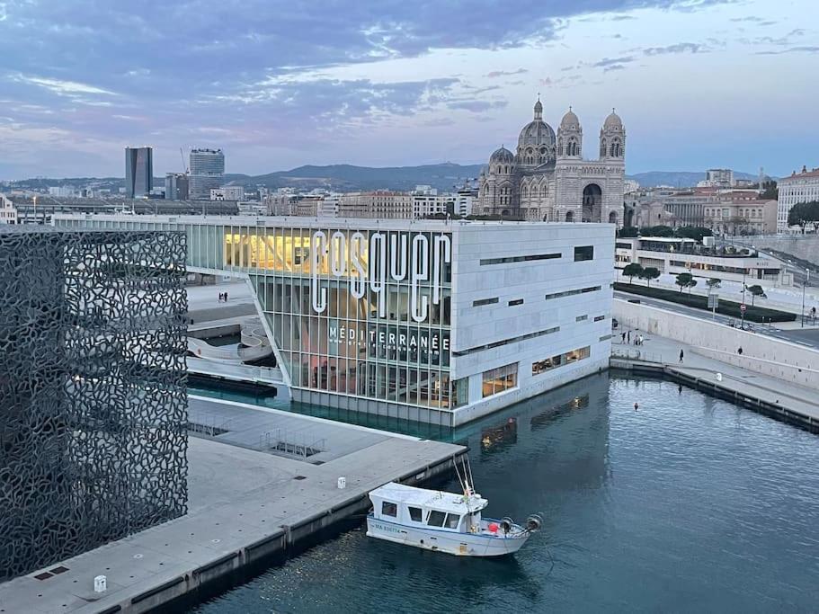 un bateau dans l'eau devant un bâtiment dans l'établissement Charmant Studio Quai Joliette, à Marseille