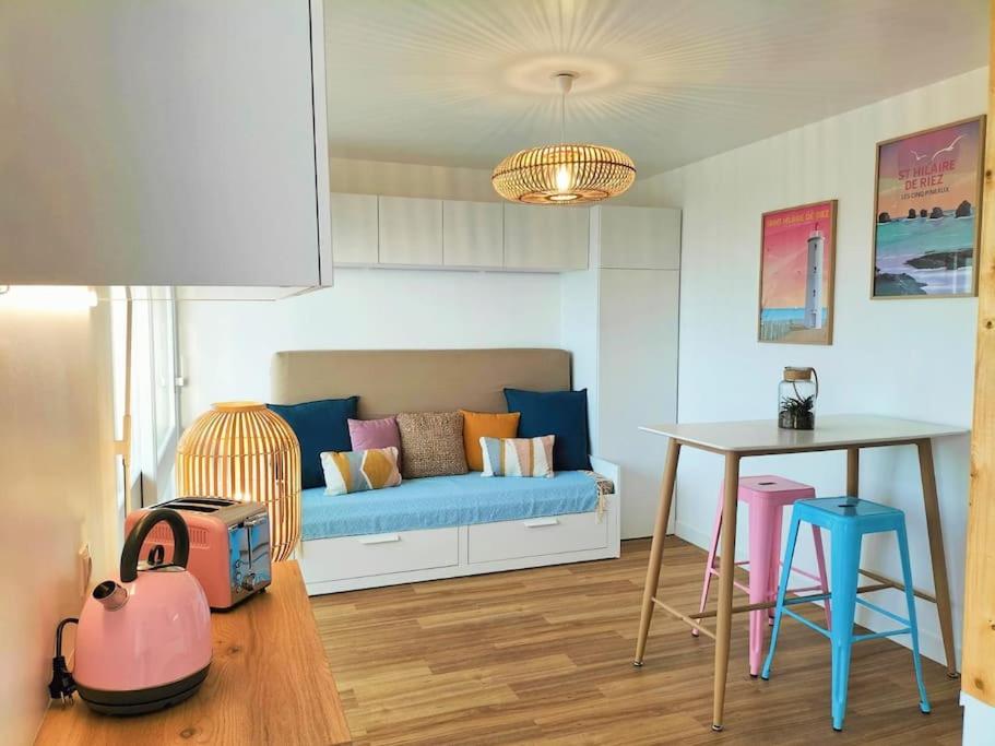 a living room with a blue couch and a table at Studio face mer pieds dans l’eau in Saint-Hilaire-de-Riez