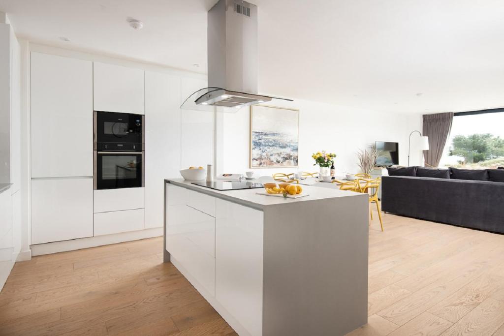 a white kitchen with a island in a living room at 1 The Bay - Stunning contemporary flat on the Scottish coast in Coldingham