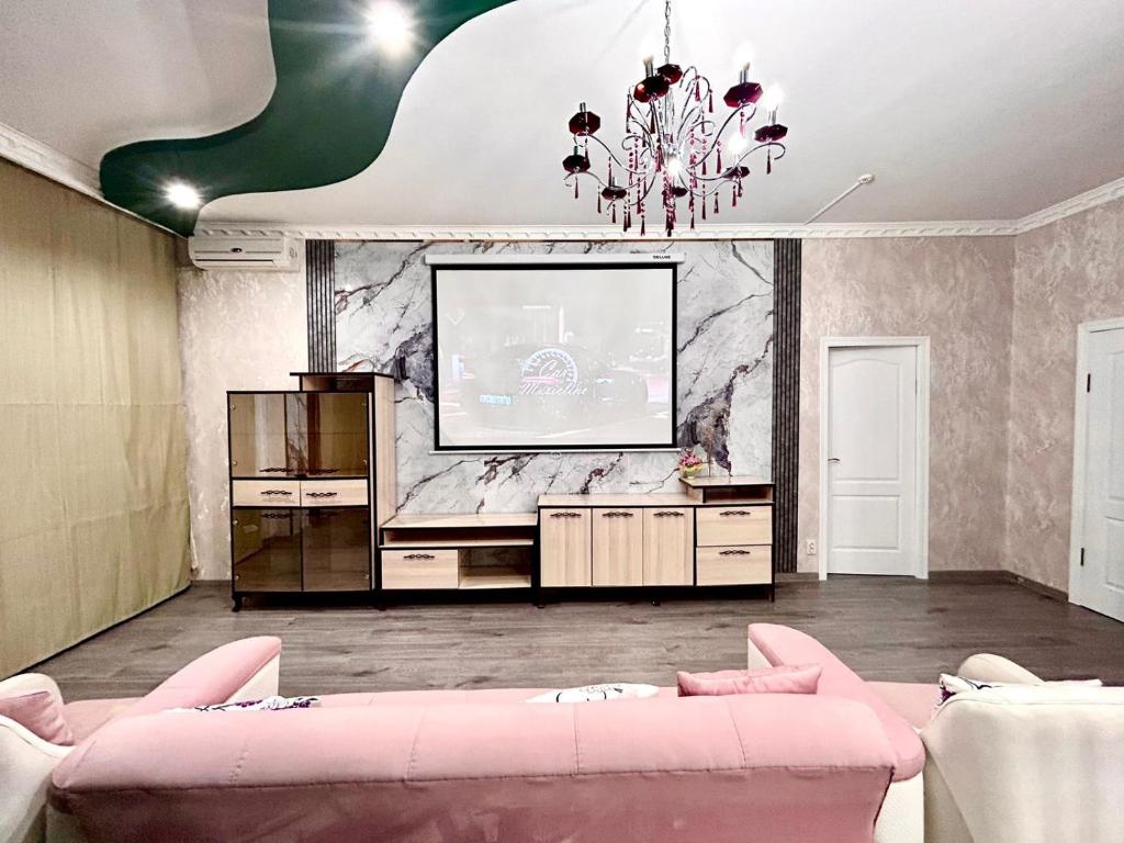 a living room with a tv and a pink couch at Просторная 3 комнатная квартира in Atyraū