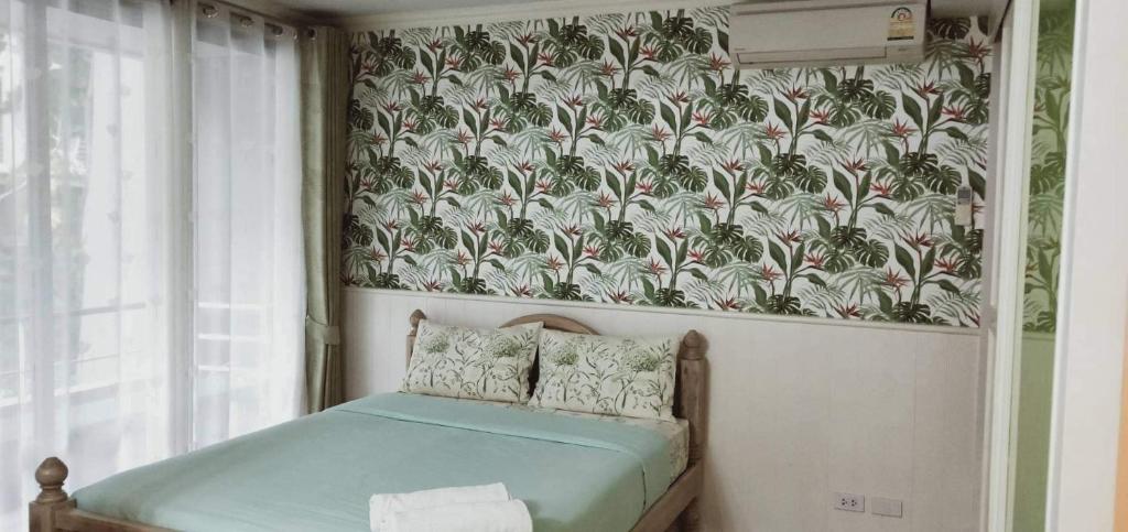 a bedroom with a bed with a tropical wallpaper at บ้านแสนคราม หัวหิน in Ban Huai Sai Tai