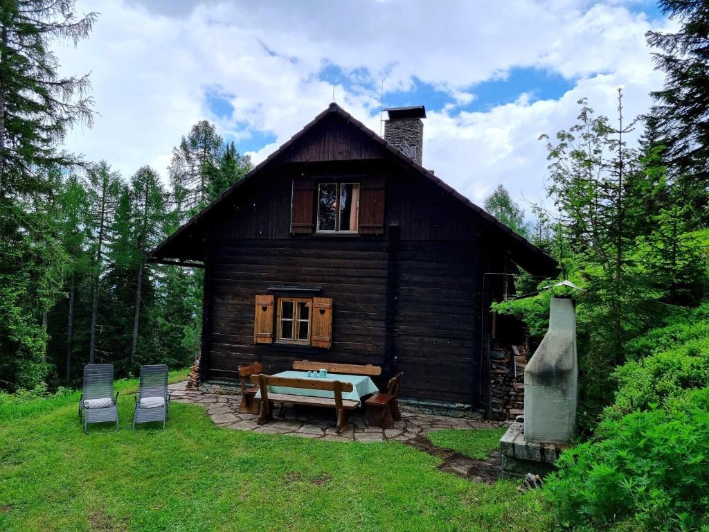 uma pequena casa de madeira com duas cadeiras em frente em Alpine hut in St Lorenzen ob Murau Styria 