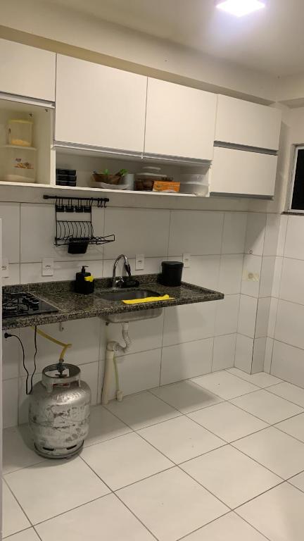 una cucina con armadi bianchi e una pentola sul pavimento di Aconchego a Petrolina
