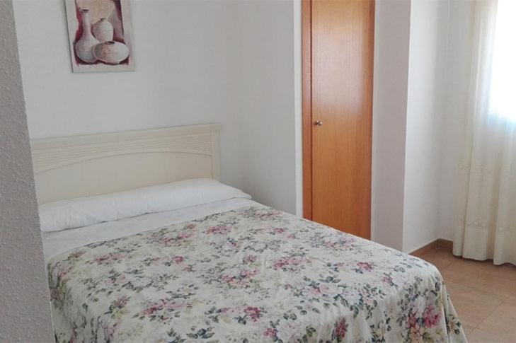 - une chambre avec un lit et une couette à fleurs dans l'établissement Apartamentos Maruja, à Los Baños