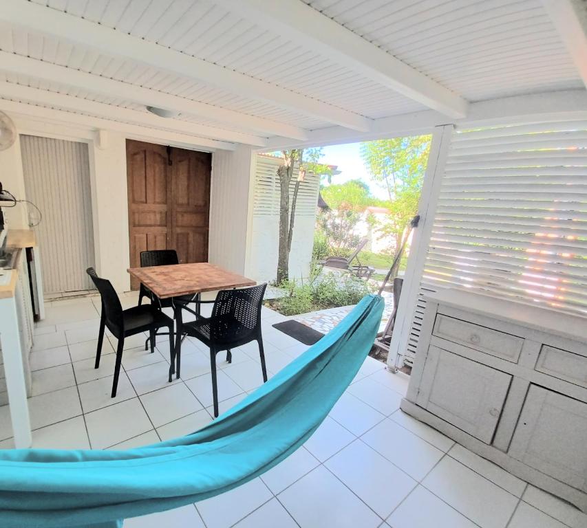 a patio with a table and a blue hammock on it at La Rose du Bresil Marie-Galante in Capesterre