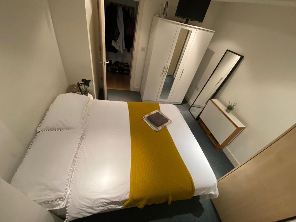 a bedroom with a bed with a yellow blanket at Private room in Camden in London