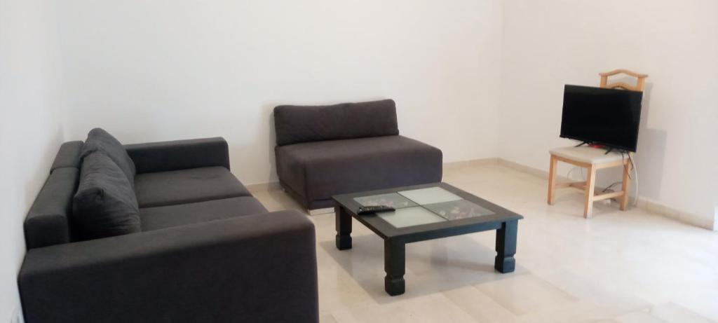 ein Wohnzimmer mit einem Sofa, einem Stuhl und einem Couchtisch in der Unterkunft Appartement luxeuse in Nassene Srhira