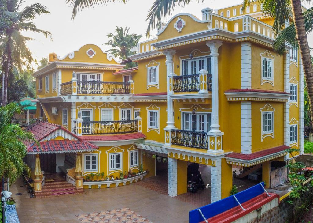 un grand bâtiment jaune avec des fenêtres et des balcons blancs dans l'établissement The Royal Oasis Goa, à Majorda