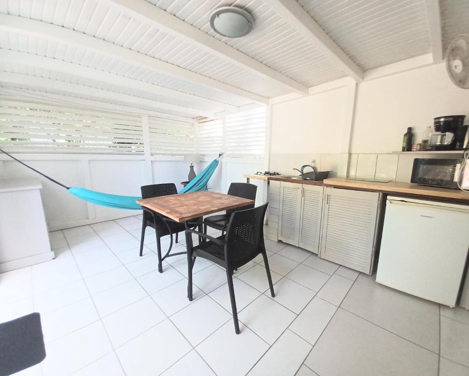 a kitchen with a table and chairs in a room at La Rose du Bresil Marie-Galante in Capesterre