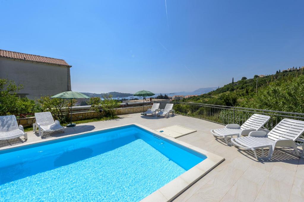 a swimming pool with chaises and chairs on a balcony at Guest House Villa Bellevue in Cavtat