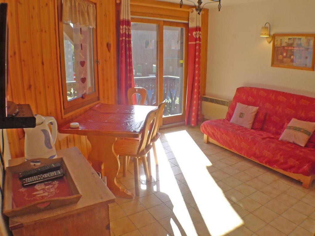 un salon avec un canapé rouge et une table dans l'établissement Charmant T2 avec mezzanine au cœur de Samoëns dans la résidence Les Campannes - FR-1-629-68, à Samoëns