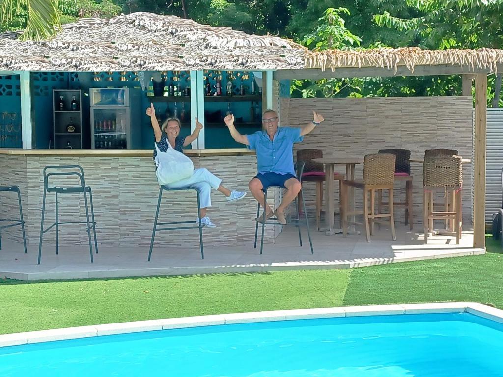 a man and a woman sitting on chairs next to a pool at La Rose du Bresil Marie-Galante in Capesterre