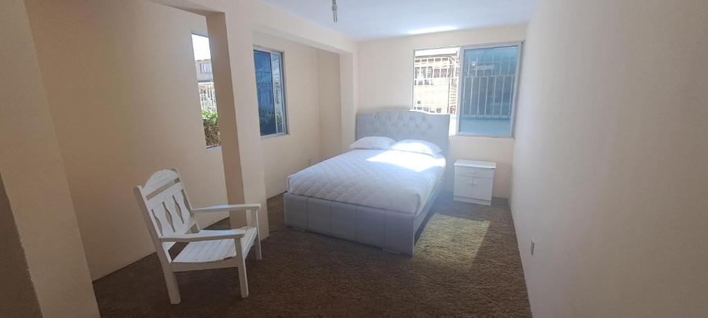 a bedroom with a bed and a chair and two windows at Habitacion privada en Departamento in La Paz