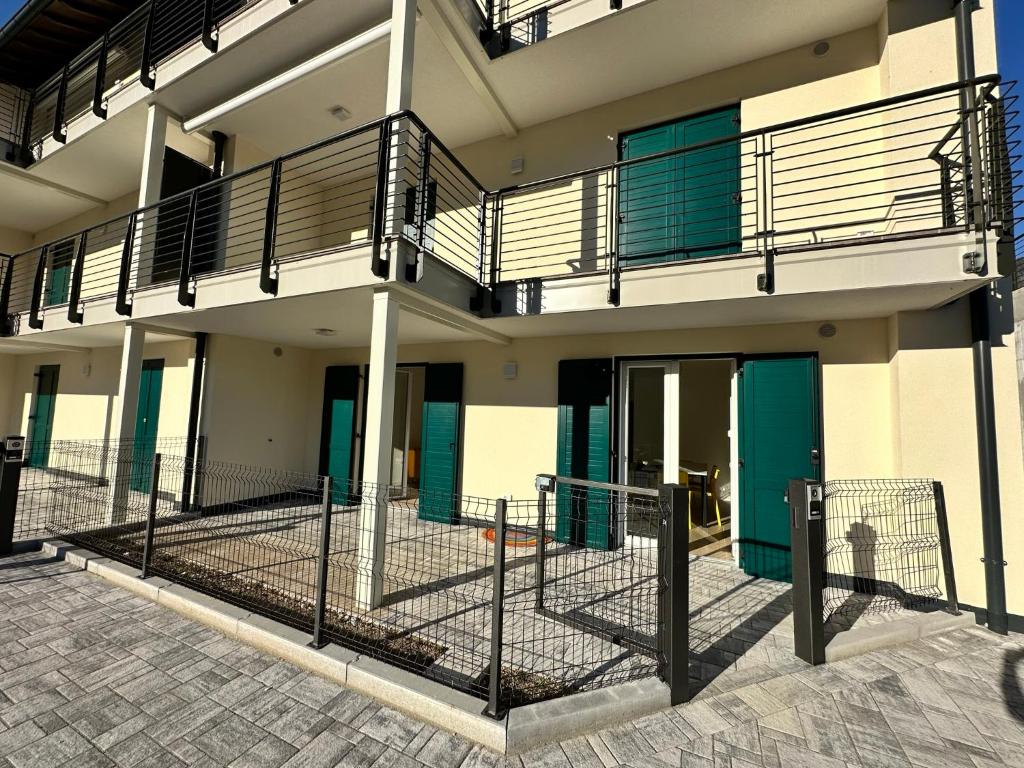 ein Gebäude mit grünen Türen und einem Zaun in der Unterkunft Appartamento Getaway Ledro in Ledro