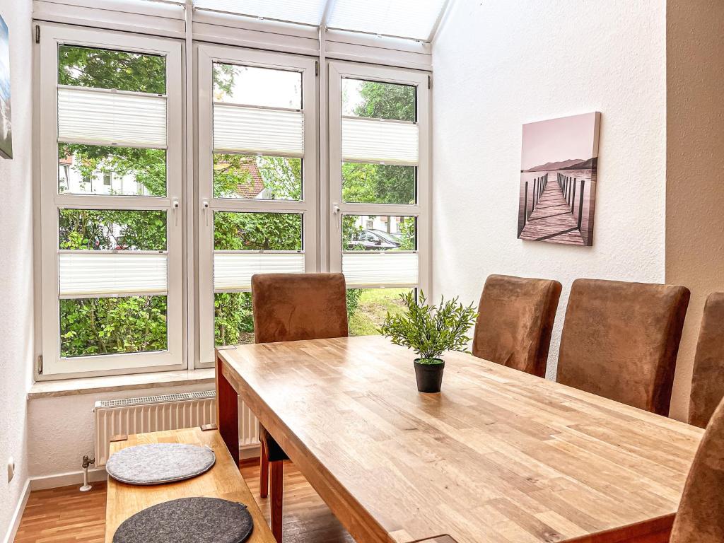 a dining room with a wooden table and some windows at Sünnslag Wohnung 131 in Boltenhagen