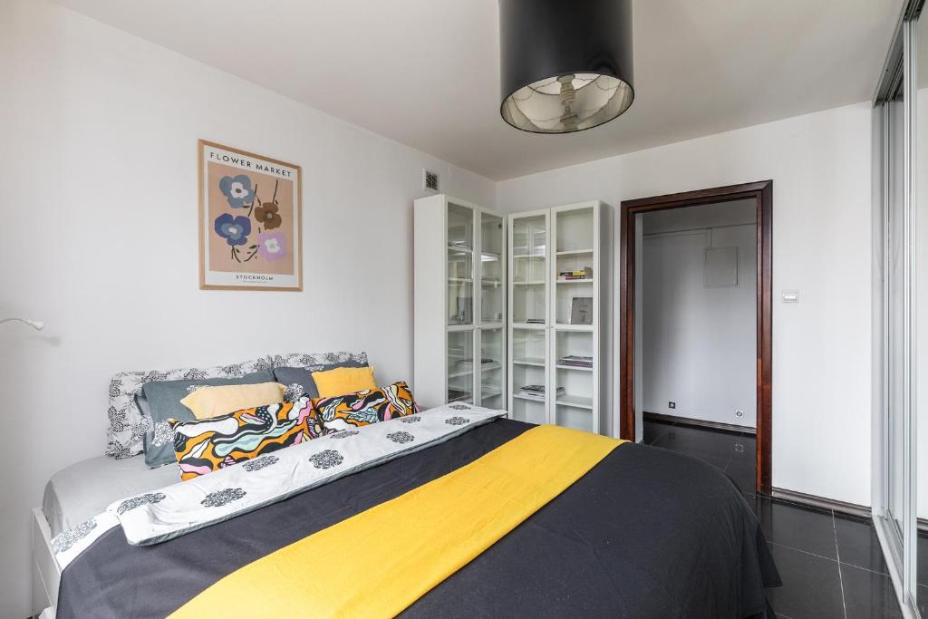 a bedroom with a bed with a yellow and black blanket at SuperApart Puławska 119 in Warsaw