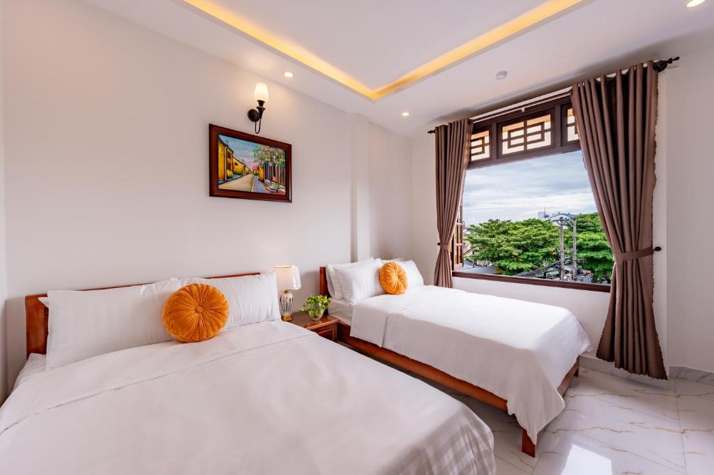 two beds in a room with a window at Golden Sun Hotel Hoi An in Hoi An