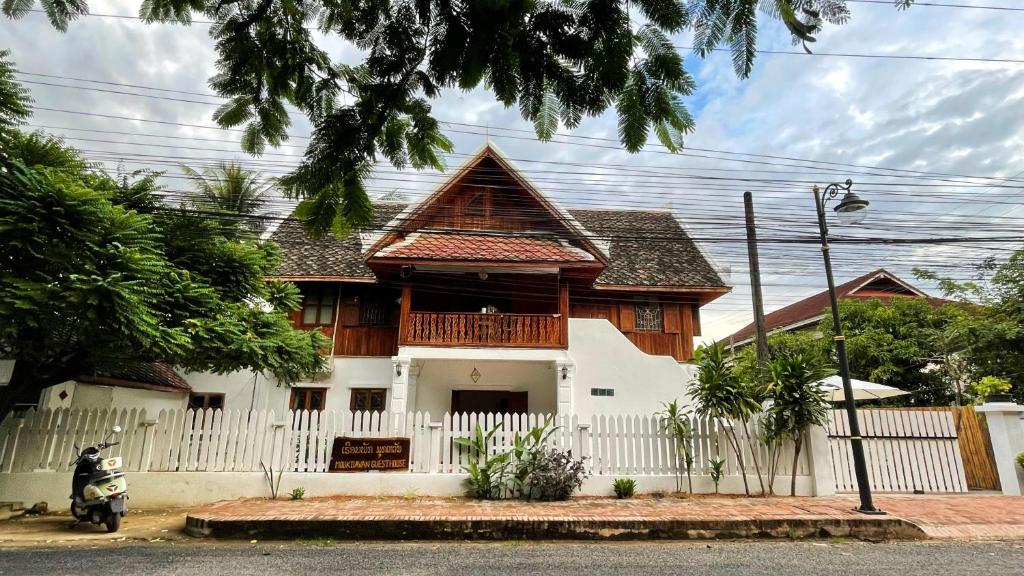 a house with a white fence in front of it at Moukdavan Guesthouse in Luang Prabang