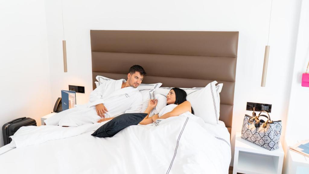 un hombre y una mujer acostados en la cama en POPULA - The Lifestyle Hotel, en Gallipoli