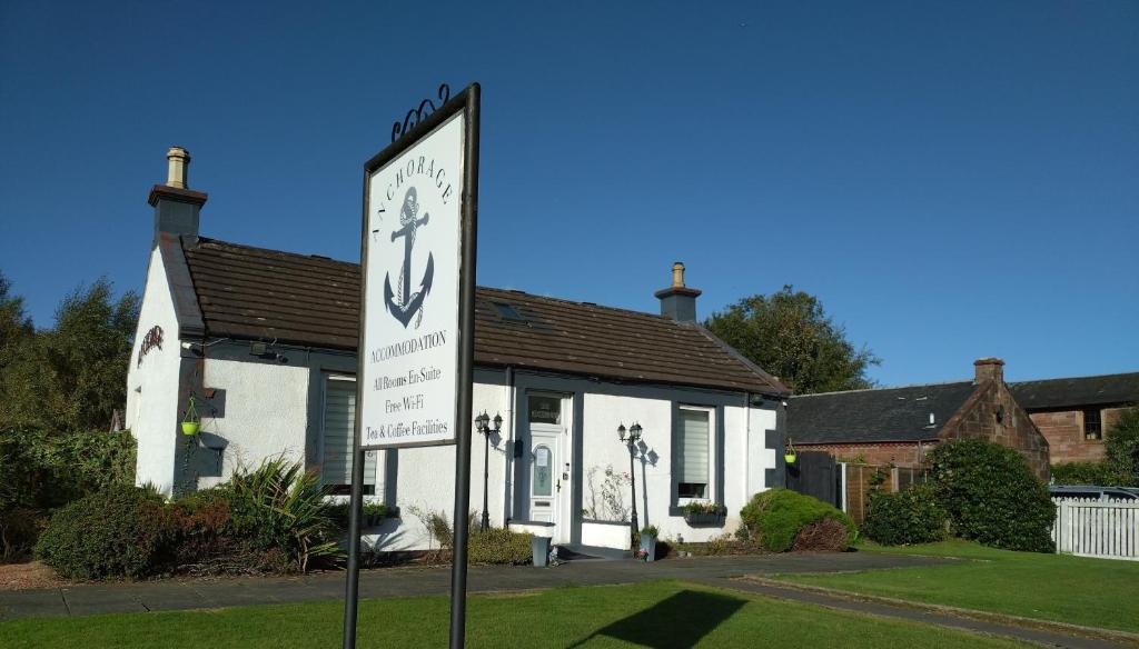 ein Schild vor einem Haus mit einer Uhr in der Unterkunft Anchorage Guest House - Also 1 room available with Hot Tub in Balloch