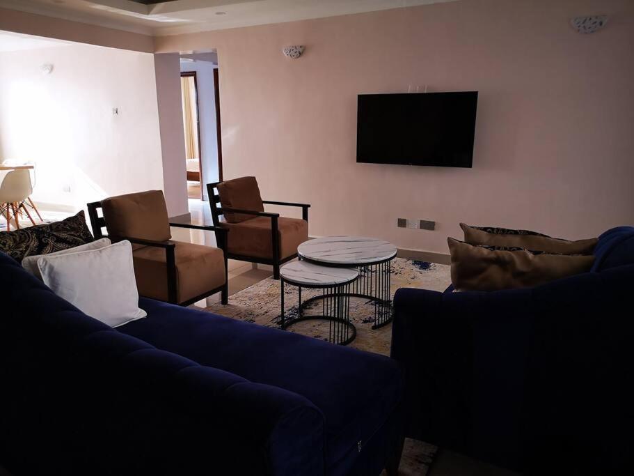 een woonkamer met een bank, een tafel en een tv bij Bee Furnished apartments 3 in Nakuru