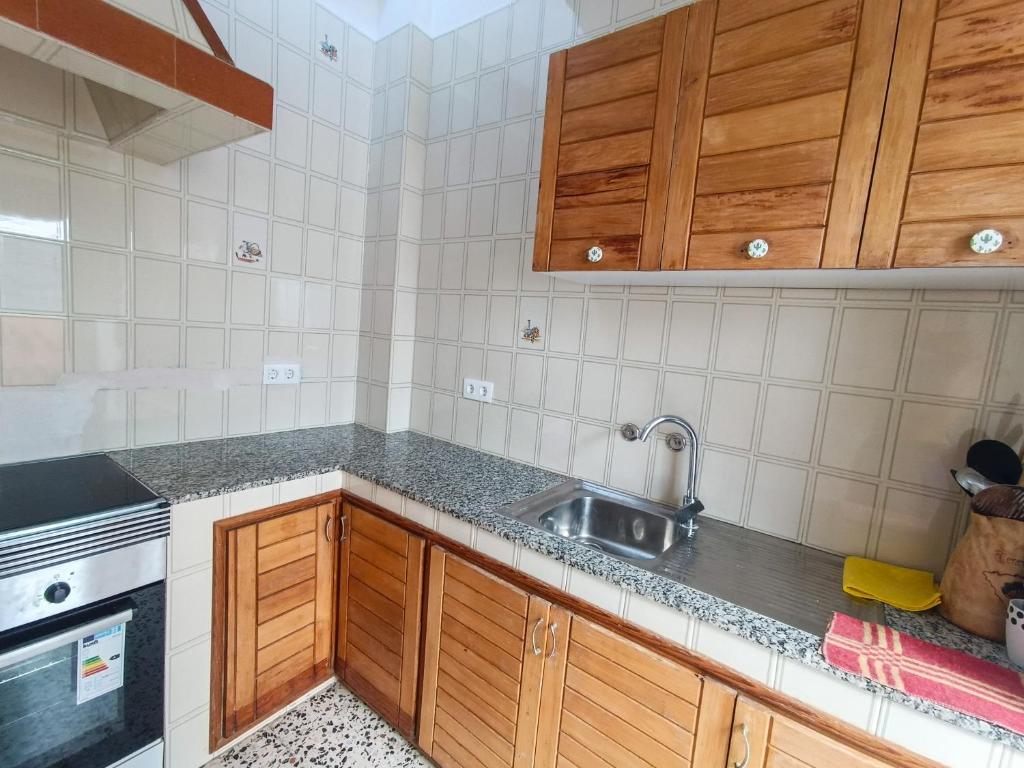 a kitchen with wooden cabinets and a sink at Daydream Medano Coliving in El Médano
