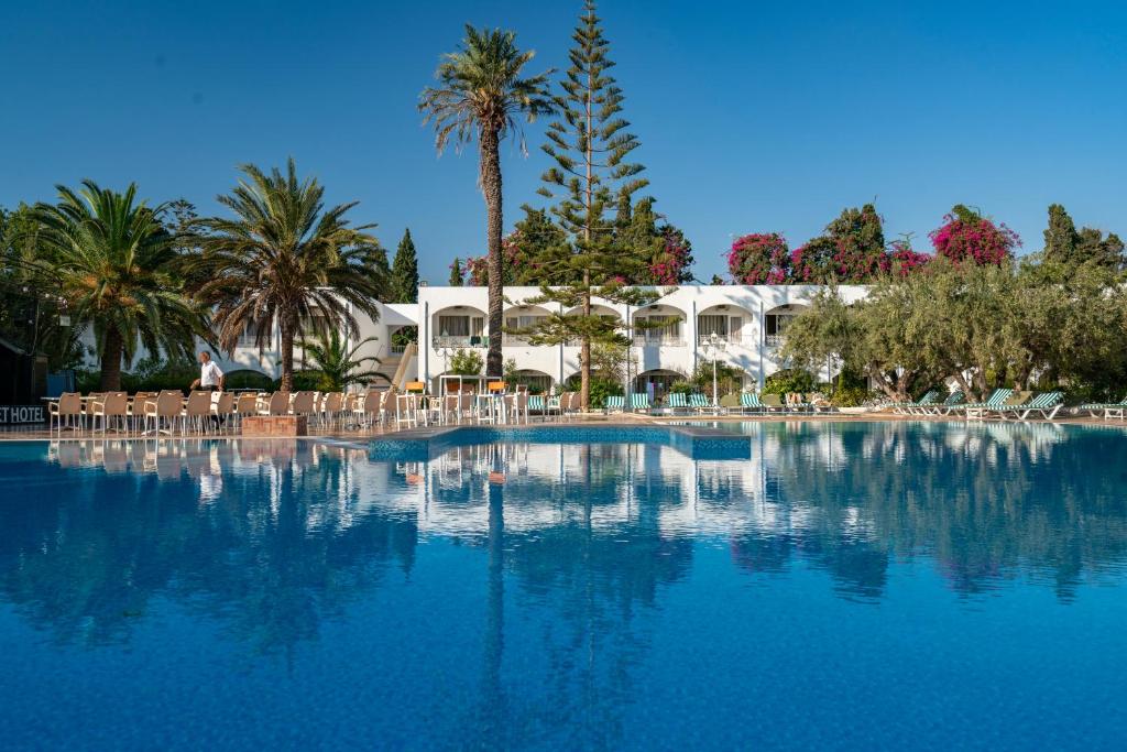 einen großen Pool mit Stühlen und Palmen in der Unterkunft Le Hammamet Hotel & SPA in Hammamet