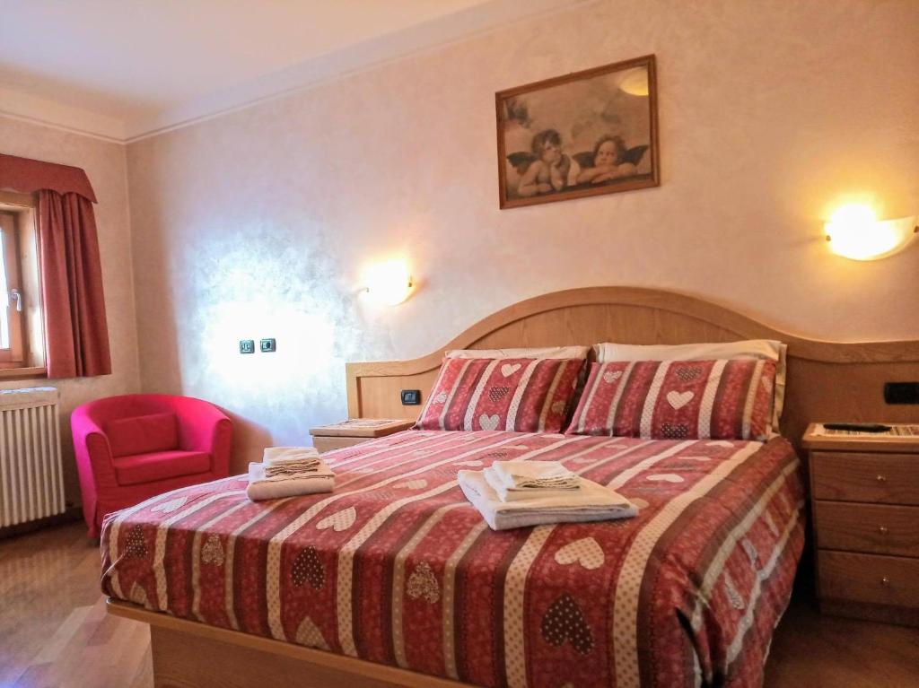 Pokój hotelowy z łóżkiem i czerwonym krzesłem w obiekcie Chalet Claudia w Livigno