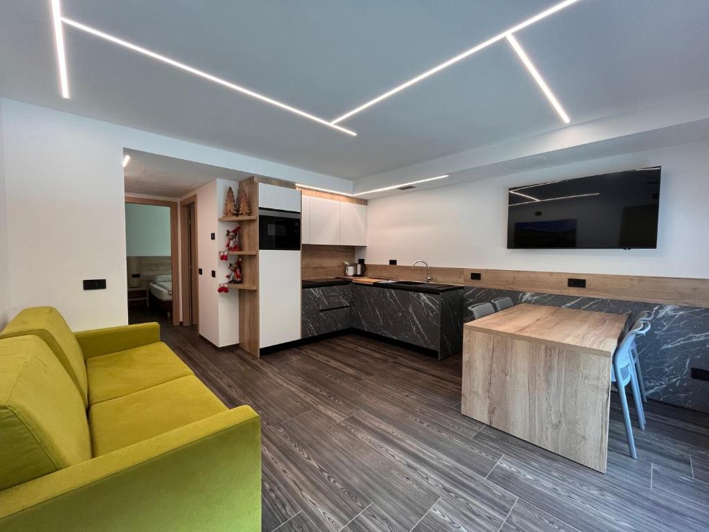 ein Wohnzimmer mit einem gelben Sofa und einem TV in der Unterkunft Gin Luxury Apartments City Centre in Livigno
