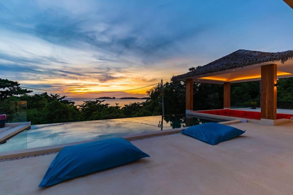 einen Sonnenuntergang auf einer Terrasse mit blauen Kissen in der Unterkunft Villa Nirvana - Wonderful Sea View in Koh Samui 