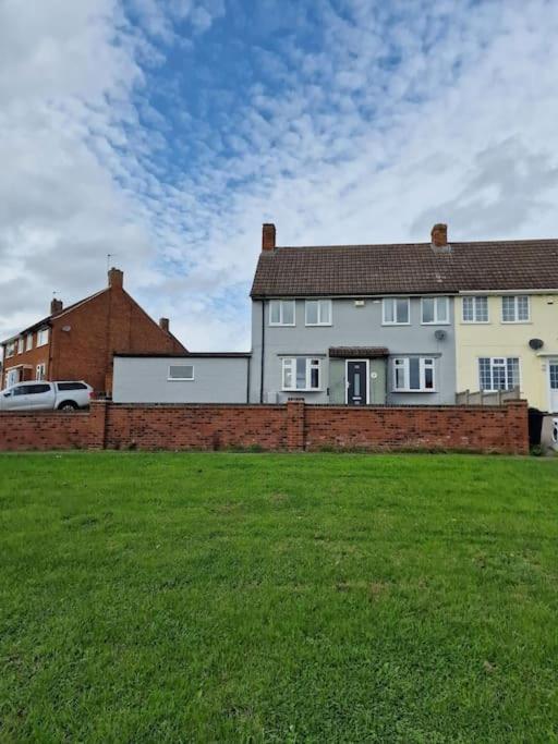 une grande maison blanche avec une clôture en briques dans une cour dans l'établissement Home in Melton Mowbray, à Melton Mowbray