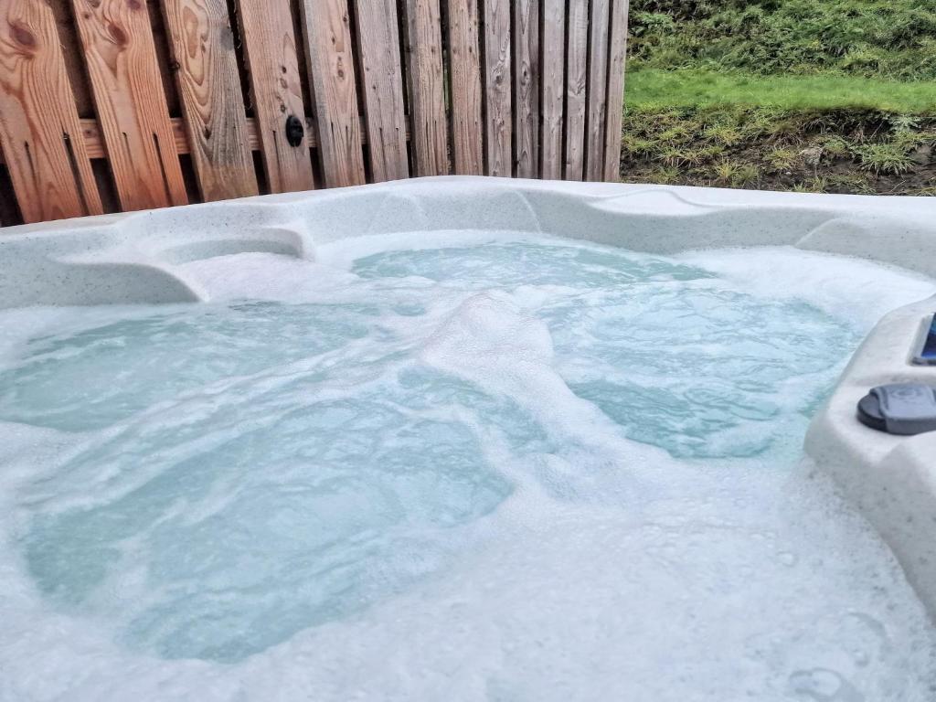 a jacuzzi tub filled with snow in a backyard at Kaoglen-Stags-Hot tub-Cairngorms-Pet Friendly in Balnald