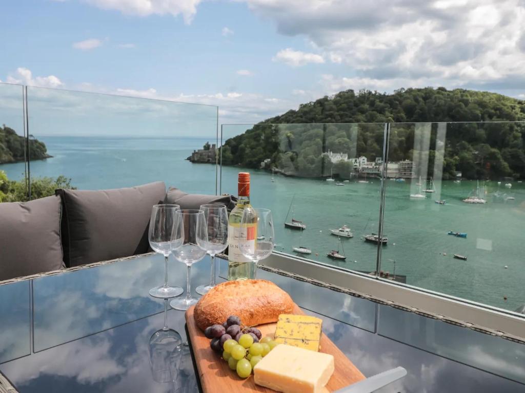 a table with wine glasses and a plate of food at Pine Lodge - Private Parking in Kingswear