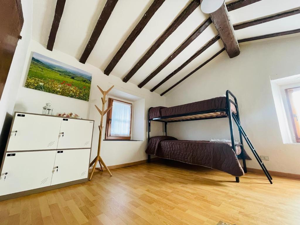 Casa del Viandante Borgo dei Sassi di Roccamalatina في Guiglia: غرفة نوم مع سرير بطابقين وأرضية خشبية