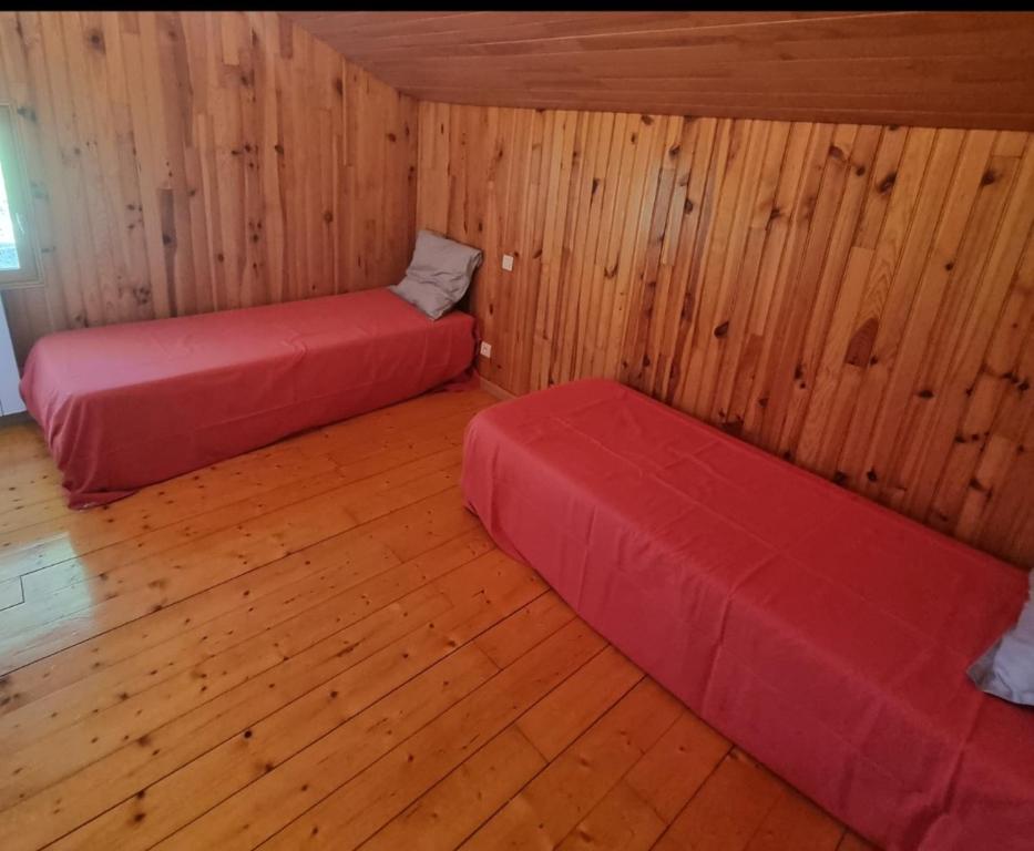 two beds in a room with wooden walls and wood floors at Maison de vacances in Sapois