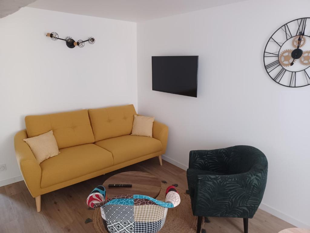 ein Wohnzimmer mit einem Sofa und einem Stuhl in der Unterkunft Duplex cosy et douillet in Ernée
