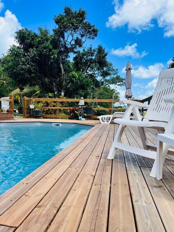 a wooden deck with a chair and a pool at Pois doux in Fort-de-France