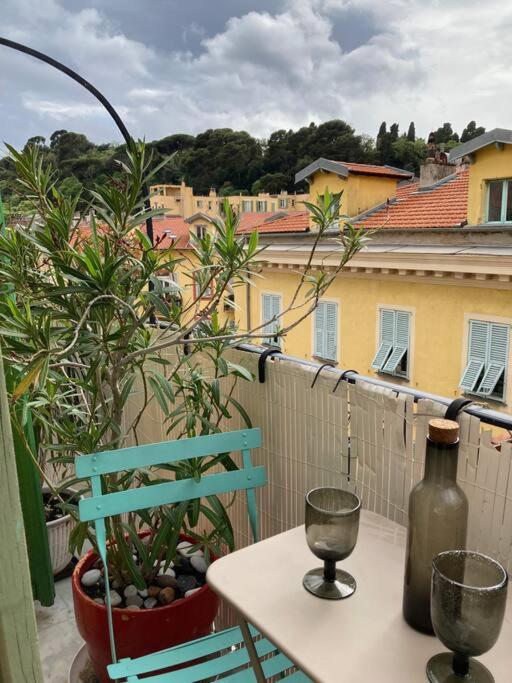 une table avec une bouteille et une chaise sur un balcon dans l'établissement Charmant deux pièces dans le quartier du Port, à Nice