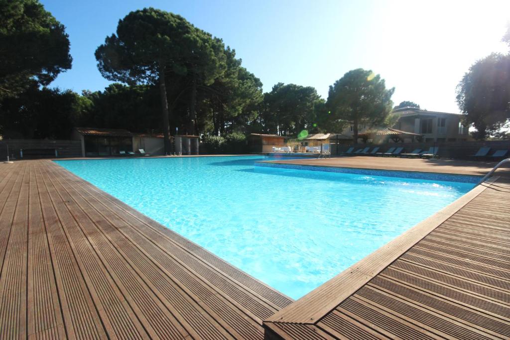une grande piscine bleue avec une terrasse en bois dans l'établissement Studio grande piscine dans résidence hôtelière, proche plage, à Lecci