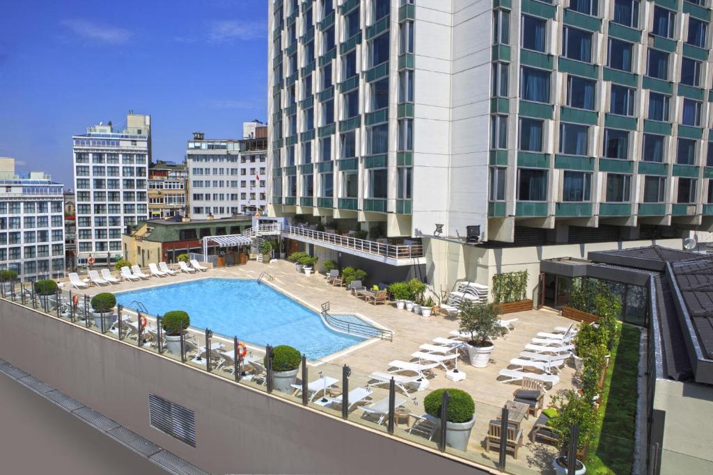 a view of a building with a pool and chairs at The Marmara Taksim in Istanbul