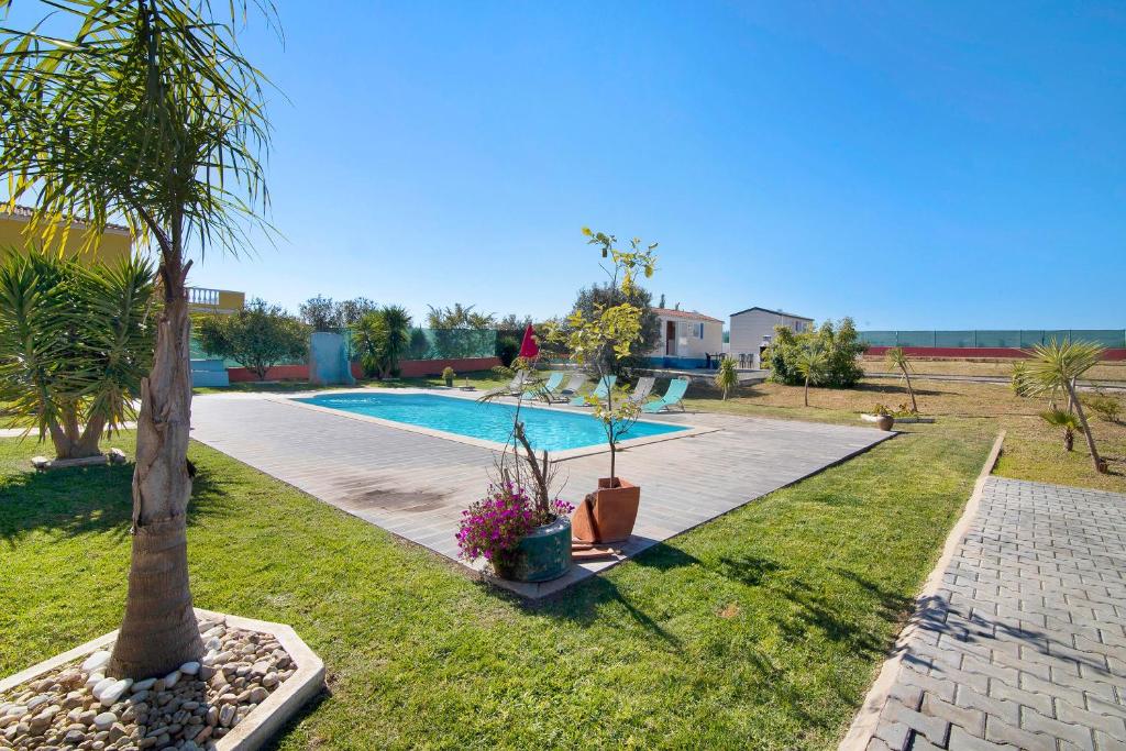 a swimming pool in a yard with a palm tree at Mobile Home 1 - Olhão in Quelfes