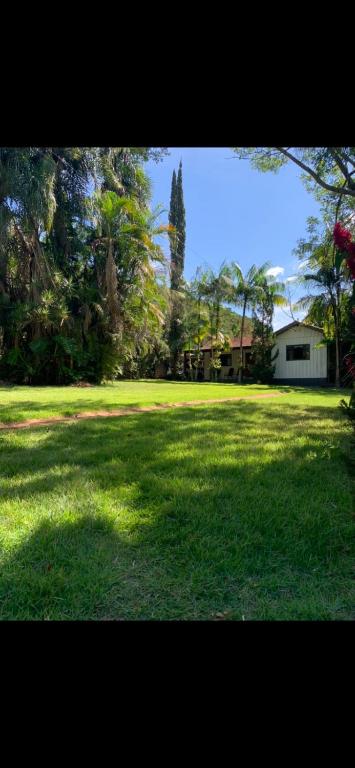 un gran campo de hierba con una casa y árboles en Recanto do sossego, en Rolândia