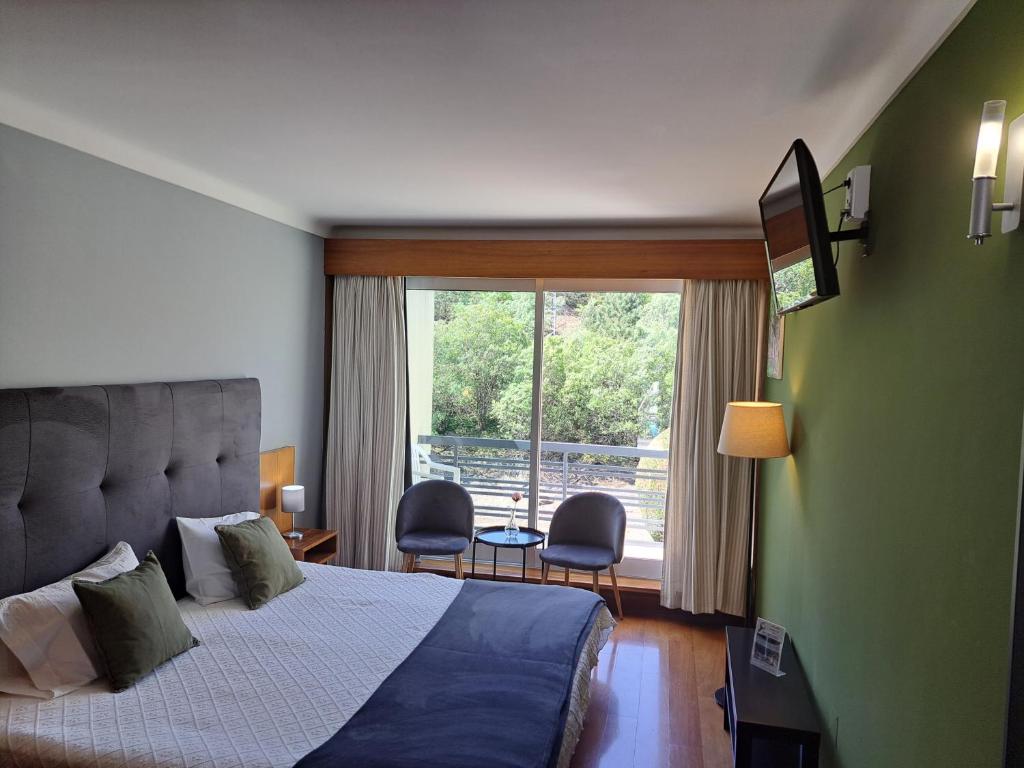 1 dormitorio con cama y ventana grande en São Cristóvão Nature Country Hotel, en Venda Nova