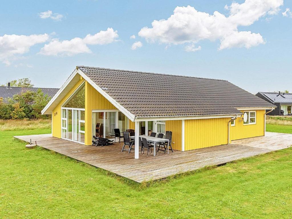 una casa amarilla con una terraza de madera en un campo en 10 person holiday home in Brovst, en Brovst