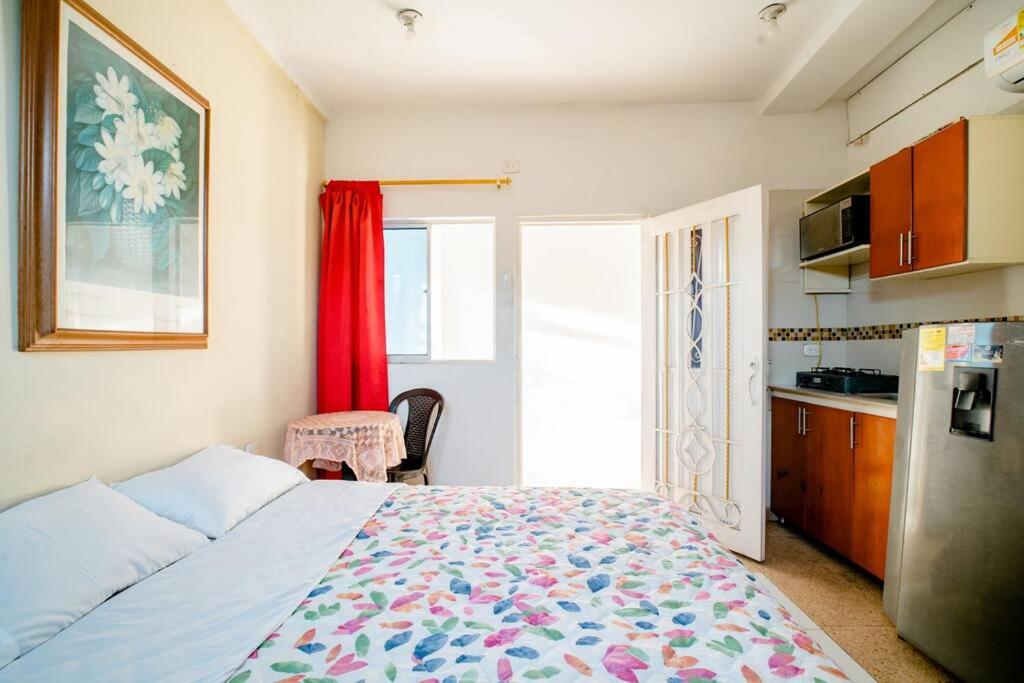 a bedroom with a bed and a kitchen with a refrigerator at APARTAESTUDIO LA 27 in Barranquilla
