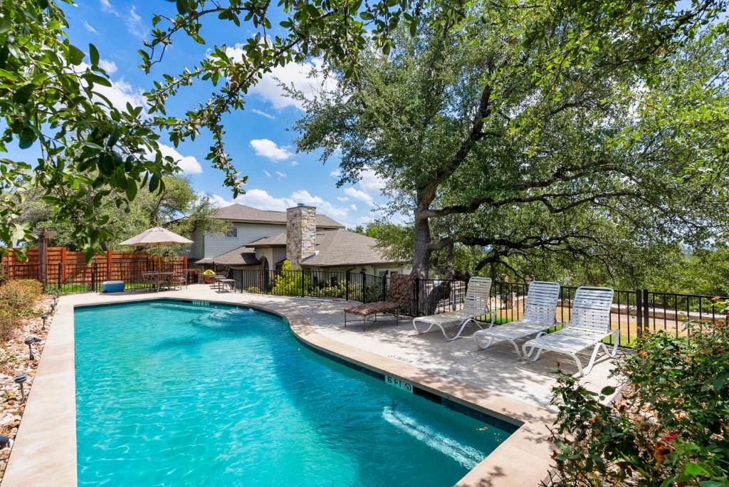 a swimming pool with chairs and a house at Brand New Lake Travis Estate - Awesome Pool in Austin